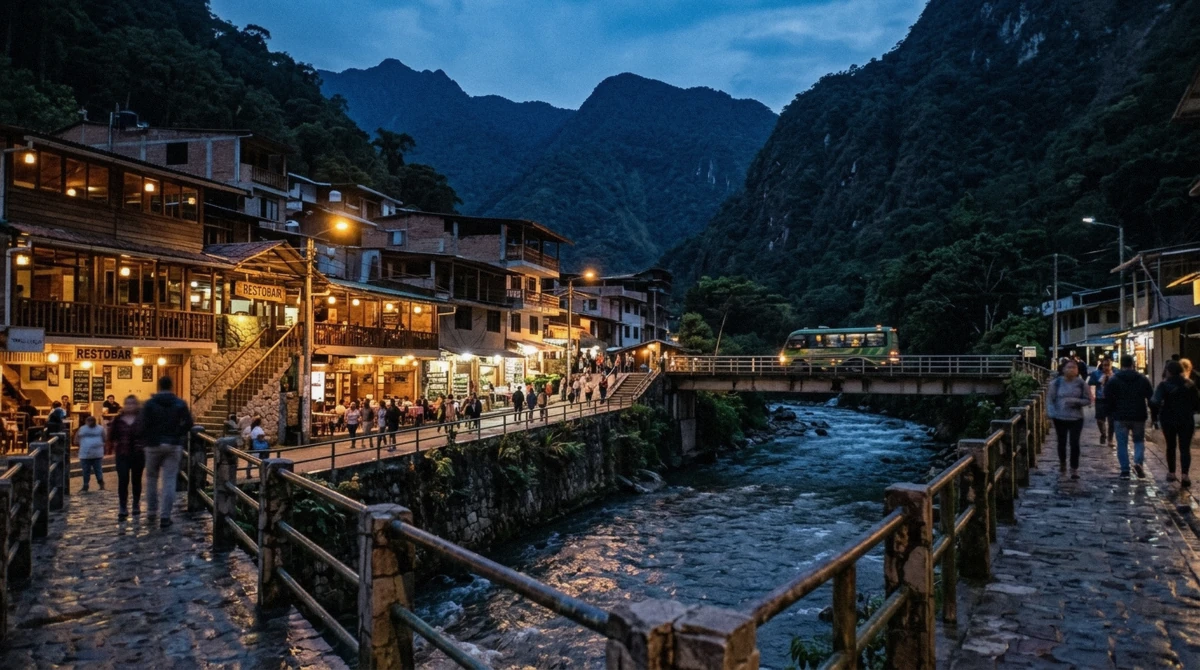 Aguas Calientes town at dusk with the river running past restaurants below forested ridges