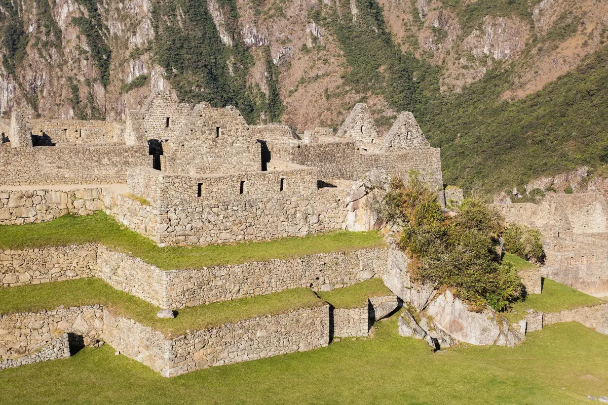 Visitors crossing the stone bridge approach on the way to Machu Picchu, Peru