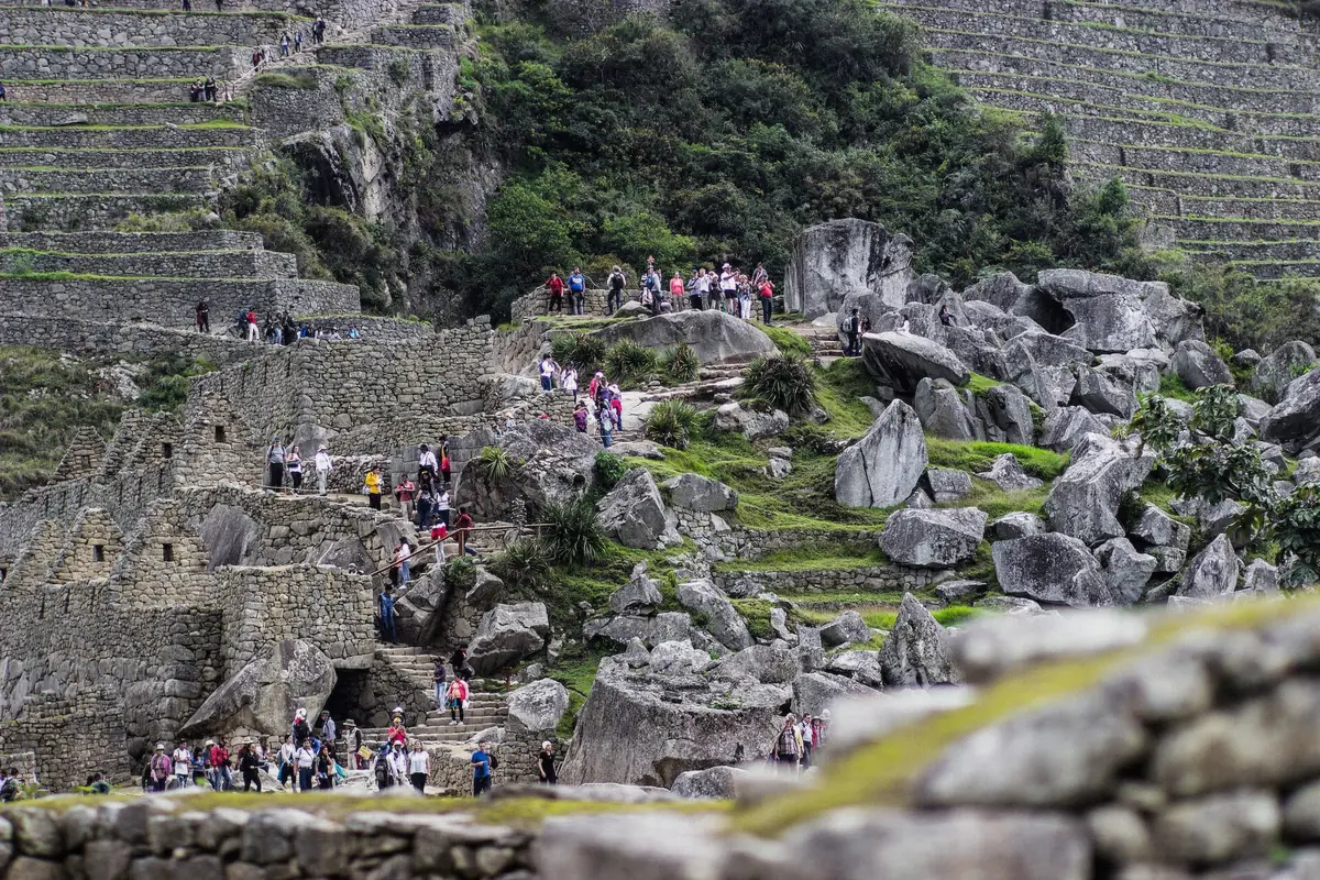 Visitors walking the stone steps between the terraces of Machu Picchu in Peru